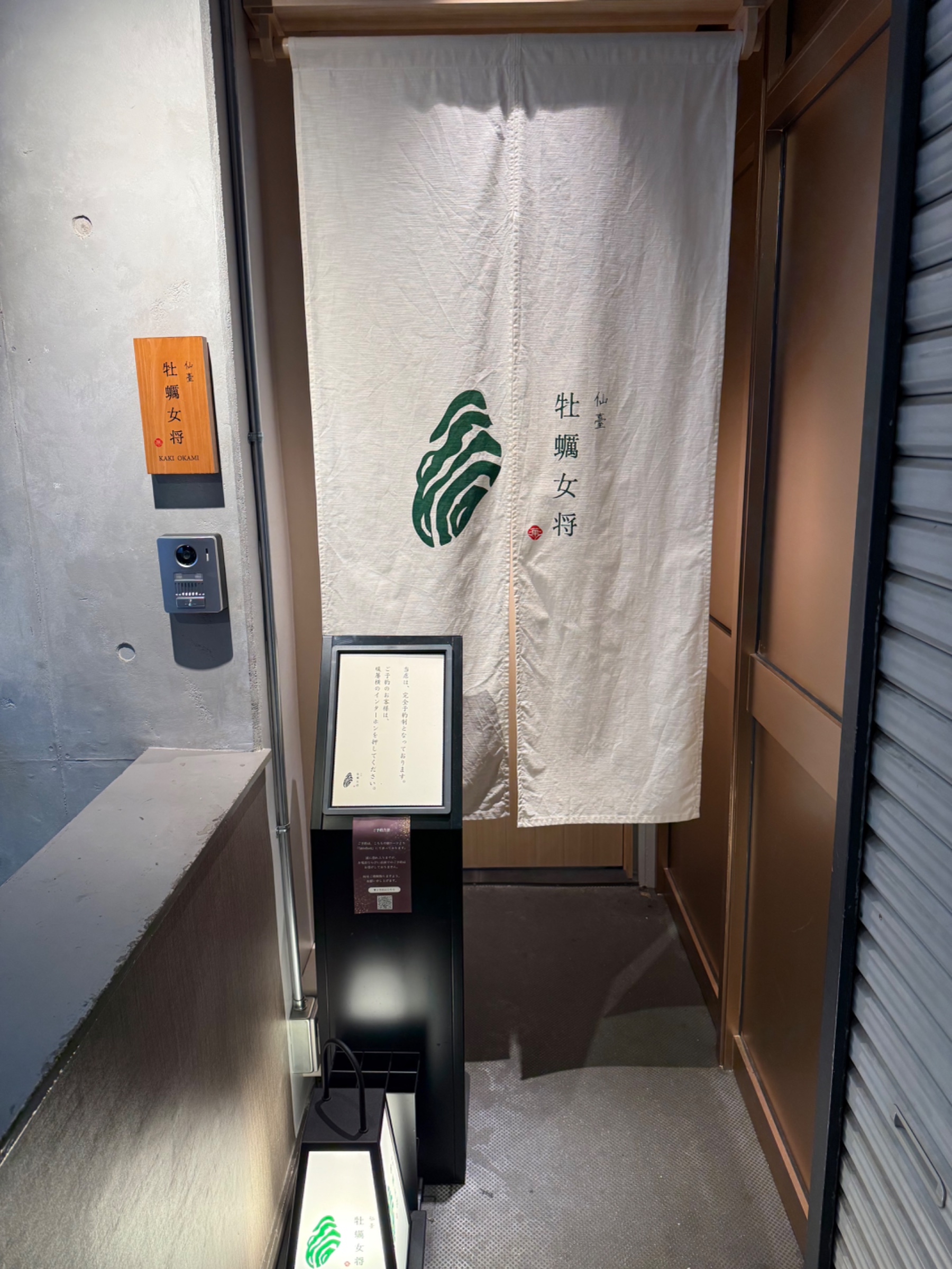 店の入り口、暖簾に「仙臺 牡蠣女将」と書かれている