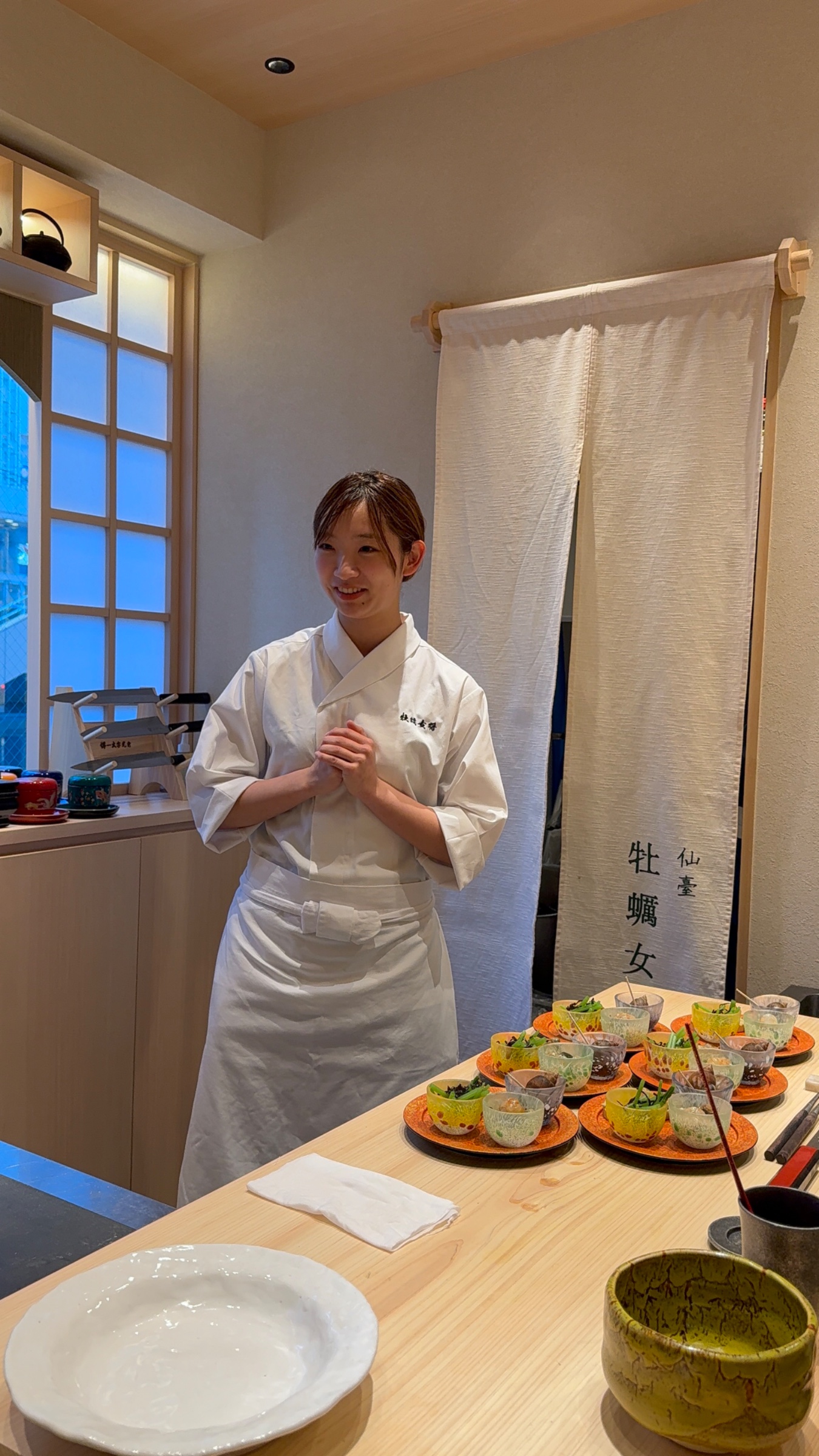 カウンター越しに笑顔で立つ女将