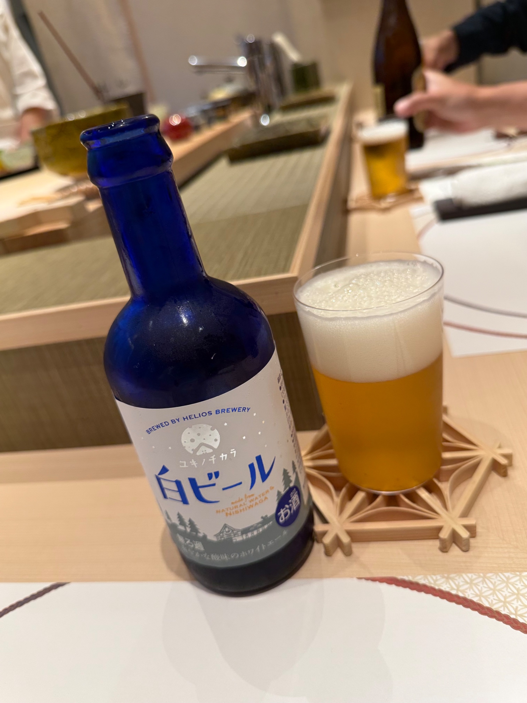 カウンター席に並ぶ白ビールのボトルとグラス