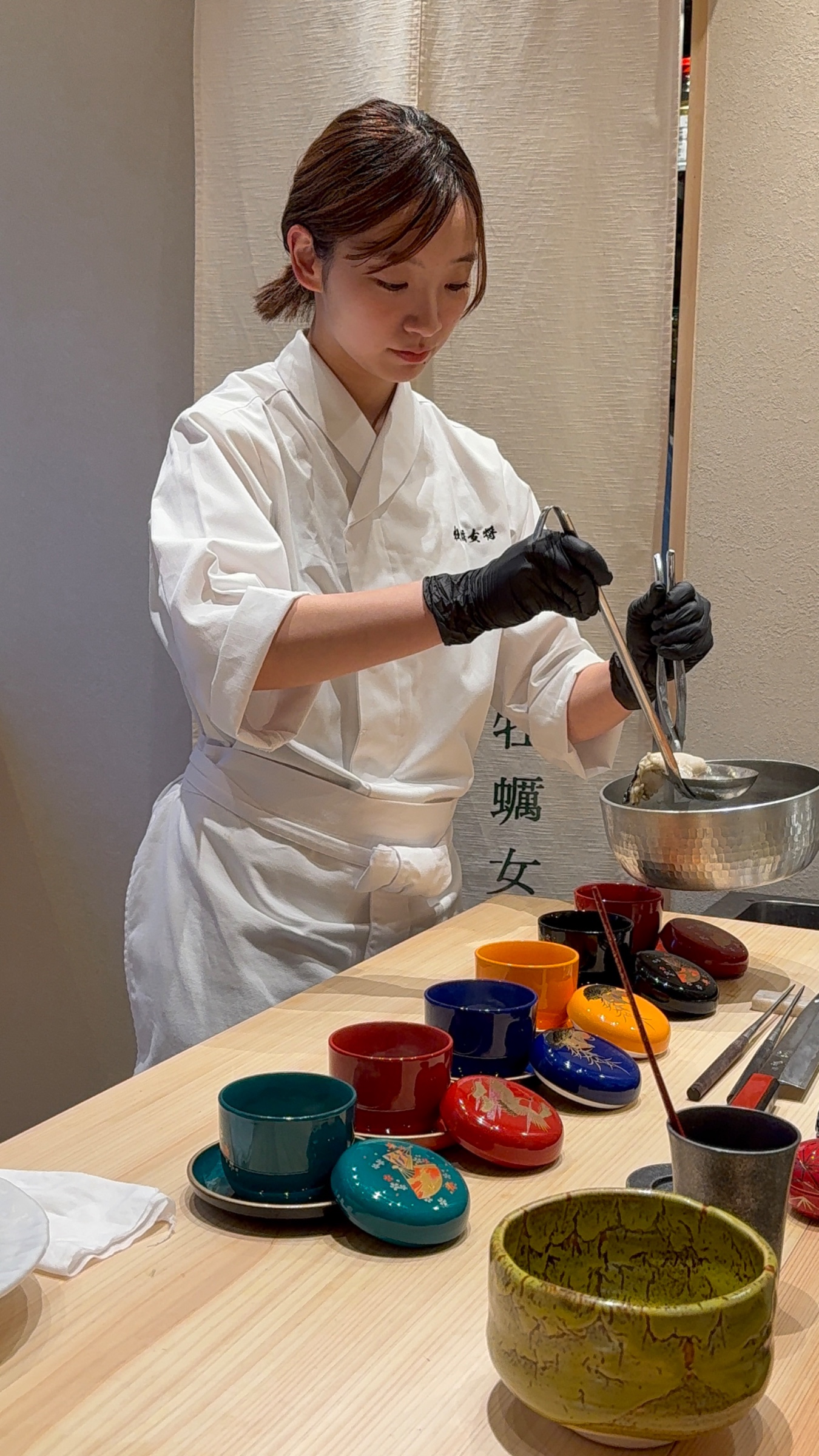 カラフルな器を前に料理を仕上げる女将